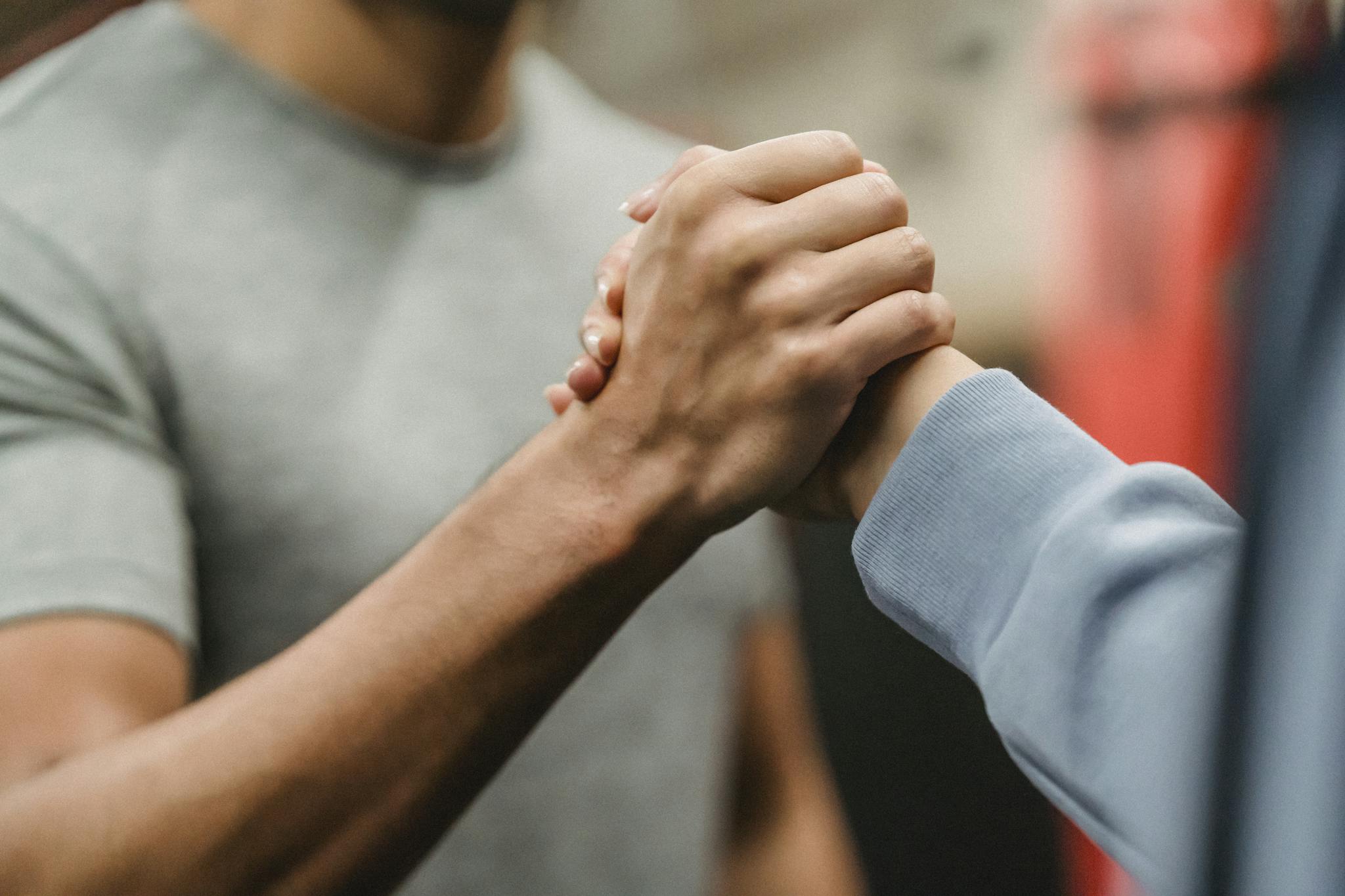 Crop sportive couple clasping hands in gym